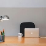 A tidy minimalist office setup featuring a laptop, desk lamp, and stationery.