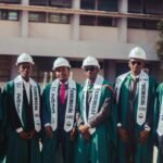 Graduates in caps and gowns celebrating chemical engineering degrees outdoors.