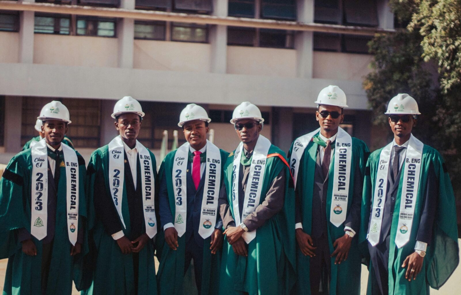 Graduates in caps and gowns celebrating chemical engineering degrees outdoors.