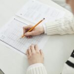Close-up of a student filling out a multiple-choice exam in a quiet classroom setting.